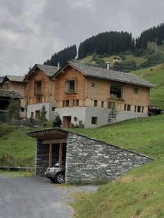 a car is parked in front of a house on the side of a mountain road