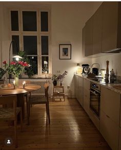 a kitchen with wooden floors and white walls is lit up by lights from the windows