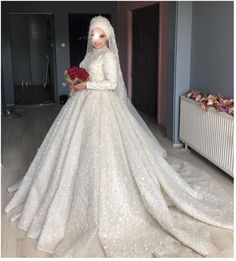 a woman in a white wedding dress with flowers on her head and veil over her face