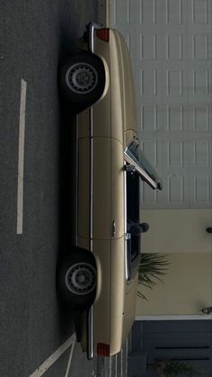 an old car is parked on the side of the road in front of a garage