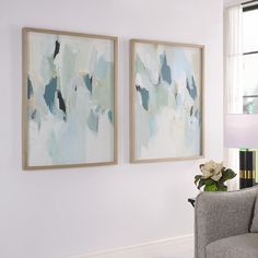 two paintings hanging on the wall in a living room next to a couch and lamp