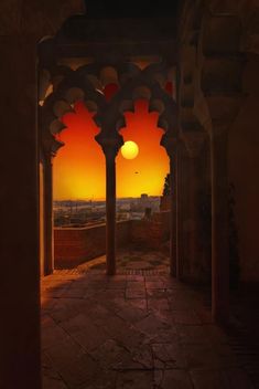 the sun is setting behind an arch in a building with columns and arches on either side