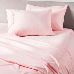 a bed with pink sheets and pillows on it