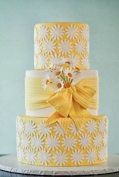 a yellow and white wedding cake with flowers on top