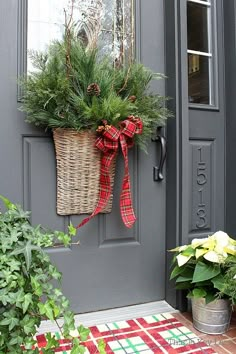 the front door is decorated for christmas with evergreens, pine cones and red plaid ribbon