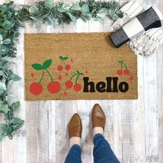 a person standing in front of a door mat with the word hello written on it