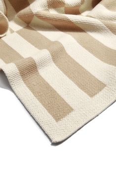 a beige and white striped blanket laying on top of a table