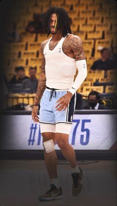 a man standing on top of a basketball court with his hands in his pockets and wearing knee pads