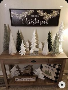 christmas decorations are displayed on a table in front of a sign that says merry christmas