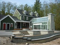 a green house with a large patio and steps leading up to it