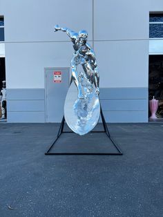 a sculpture of a man holding a surfboard in front of a building