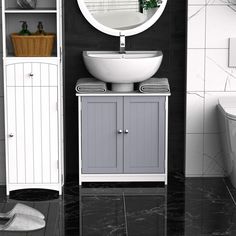 a white sink sitting next to a toilet in a bathroom on top of a black tiled floor