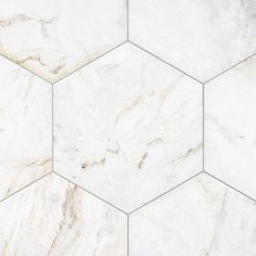 white marble hexagon tiles are arranged in an angled pattern, with grey veining on the edges