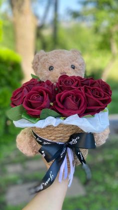 a teddy bear is holding a bouquet of roses