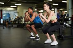 two people doing squats in a gym