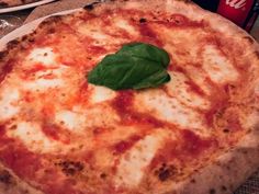 a pizza sitting on top of a white plate covered in cheese and spinach leaves