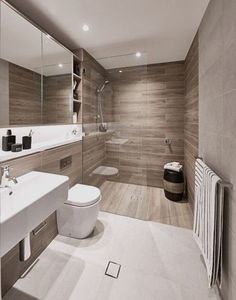 a modern bathroom with wood paneled walls and tile flooring, along with a white toilet and sink