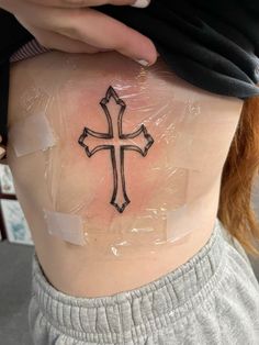 a woman with a cross tattoo on her stomach and behind her is plastic wrap covering the back of her body