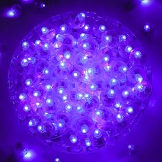 a purple light with white lights in the middle on a black surface surrounded by small round objects