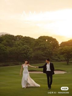 a man and woman holding hands while walking across a golf course