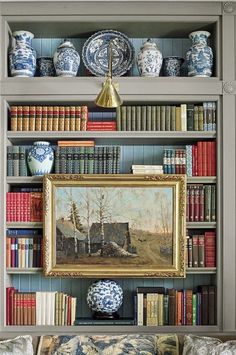 the bookshelf is filled with blue and white vases, paintings, and other decorative items