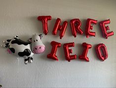 there are balloons that say three leo and a cow with a balloon attached to the wall