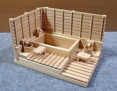 a wooden model of a japanese teahouse with benches and stools on a blue carpeted floor