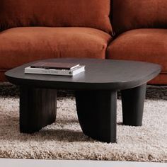 a black coffee table sitting on top of a white rug in front of a couch