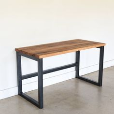 a wooden table with metal legs against a white wall