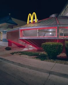 a mcdonald's restaurant lit up at night with red neon lights on the roof