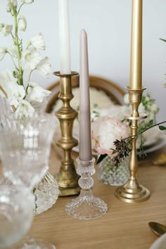 there are three candles on the table with flowers in vases next to each other