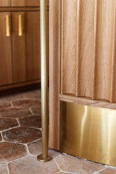 a close up of a door handle on the side of a wooden door with tile flooring