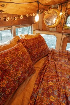 the bed is made up and has many pillows on it, along with two round mirrors