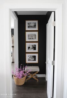 a hallway with pictures on the wall and a basket full of flowers in front of it