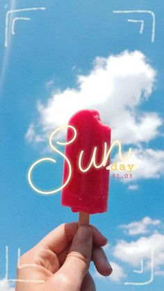 a hand holding up a popsicle with the word sun today written on it in front of a cloudy blue sky