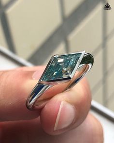 a person holding a ring with a green diamond in it