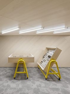 two yellow stools sitting next to each other in front of a wooden wall and floor