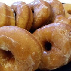 several glazed donuts stacked on top of each other in a blue plate with white icing