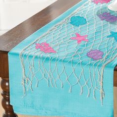 a blue table runner with pink and purple fish on it