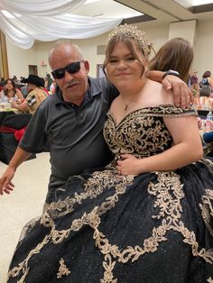 an older man and young woman in formal wear posing for the camera at a party