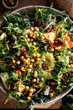 a salad with chickpeas, carrots and spinach in a bowl on a wooden table