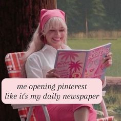 a woman sitting in a chair with a pink cat hat on reading a book and smiling at the camera