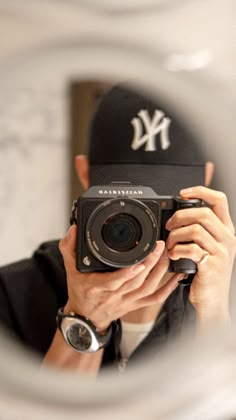 a man taking a photo in front of a mirror with a baseball cap on his head