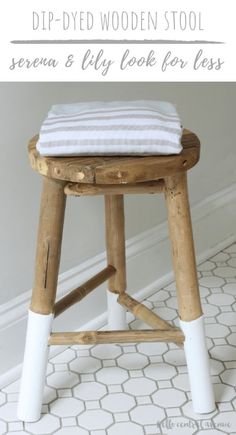 a wooden stool with white legs and a striped towel on top