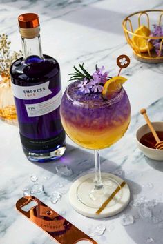 a purple and yellow drink sitting on top of a table next to a bottle of liquor