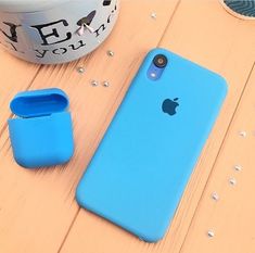 an iphone case sitting on top of a wooden table next to a cup and container