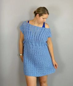 a woman standing in front of a wall wearing a blue crochet dress