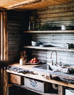 a rustic kitchen with wooden shelves and open shelving above the sink is filled with fruit