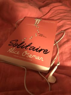 there is a book on the bed with headphones attached to it and an earphone plugged in