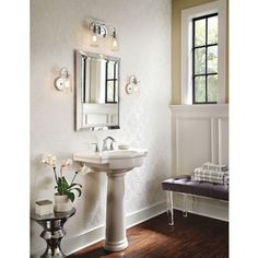 a white sink sitting under a bathroom mirror next to a window with light bulbs on it